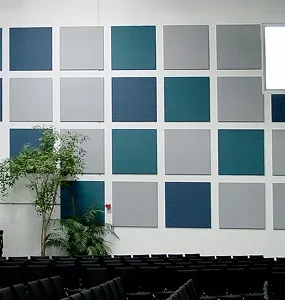 A modern wall featuring a grid of blue, gray, and green soundproofing panels