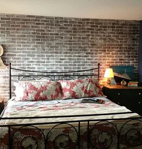 Cozy bedroom featuring a metal bed frame and a brick accent wall