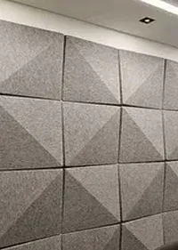 Gray wall panels with a geometric design, featuring raised, triangular patterns for sound absorption and aesthetic appeal